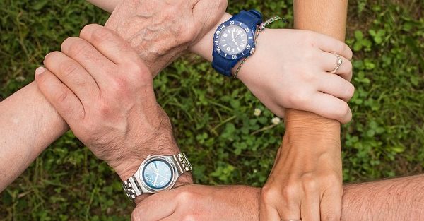 team spirit - four hands hold each other to make a square shape.