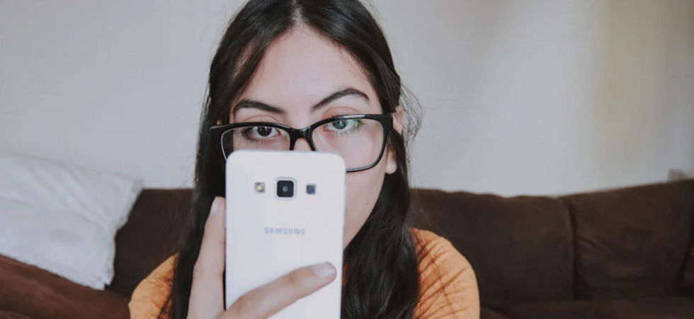 student girl with phone and wearing glasses.